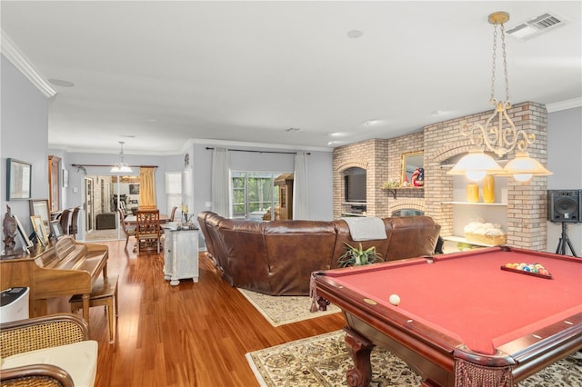 game room featuring billiards, crown molding, a chandelier, a fireplace, and hardwood / wood-style flooring