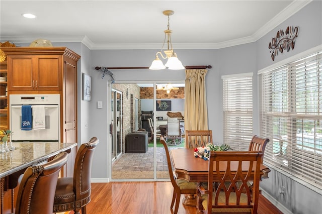 dining area with crown molding, light hardwood / wood-style flooring, and an inviting chandelier