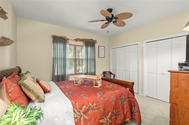 carpeted bedroom featuring ceiling fan and two closets