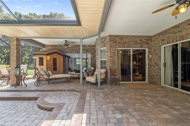 view of patio featuring glass enclosure and a storage unit