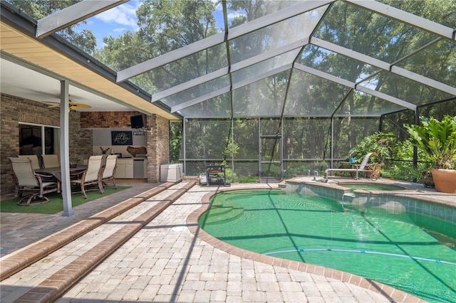 view of pool with ceiling fan, a patio area, exterior kitchen, and an in ground hot tub