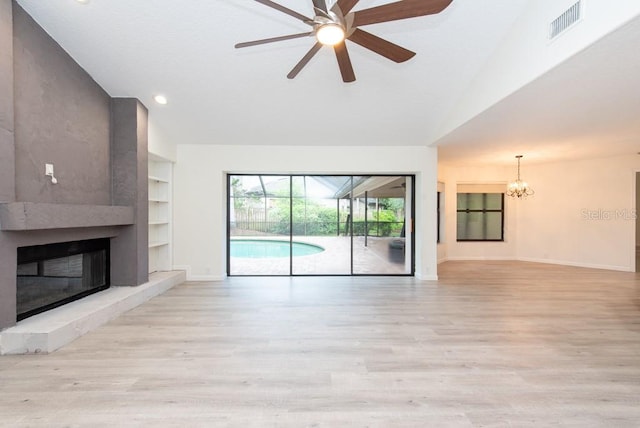 unfurnished living room featuring ceiling fan with notable chandelier, built in features, a high end fireplace, and light wood-type flooring