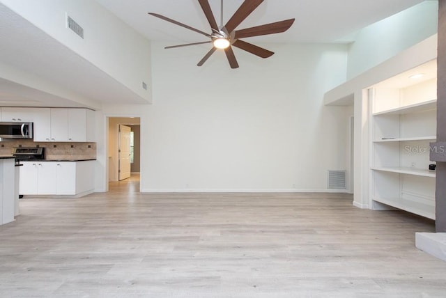 unfurnished living room with light hardwood / wood-style flooring, ceiling fan, and a high ceiling