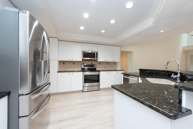 kitchen featuring decorative backsplash, white cabinets, sink, light hardwood / wood-style floors, and appliances with stainless steel finishes