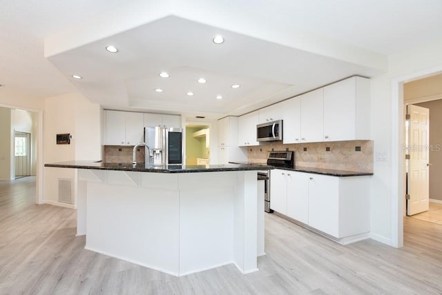 kitchen featuring decorative backsplash, appliances with stainless steel finishes, light hardwood / wood-style flooring, and white cabinetry