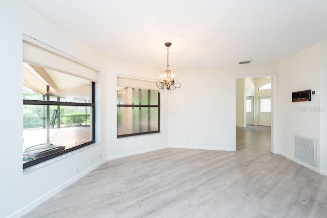 spare room featuring an inviting chandelier and light hardwood / wood-style flooring