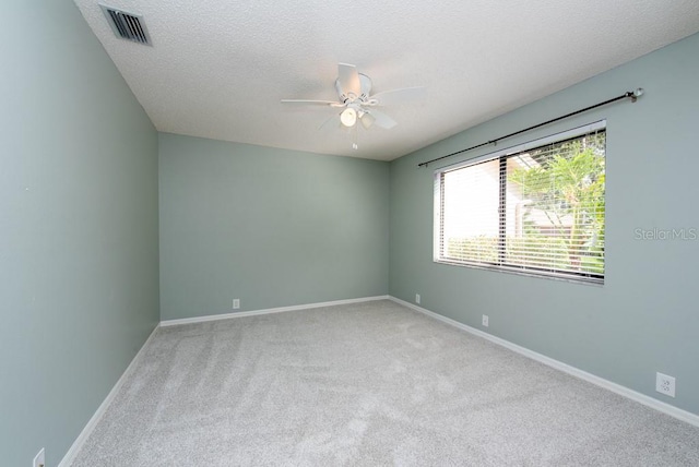 carpeted spare room featuring a textured ceiling and ceiling fan