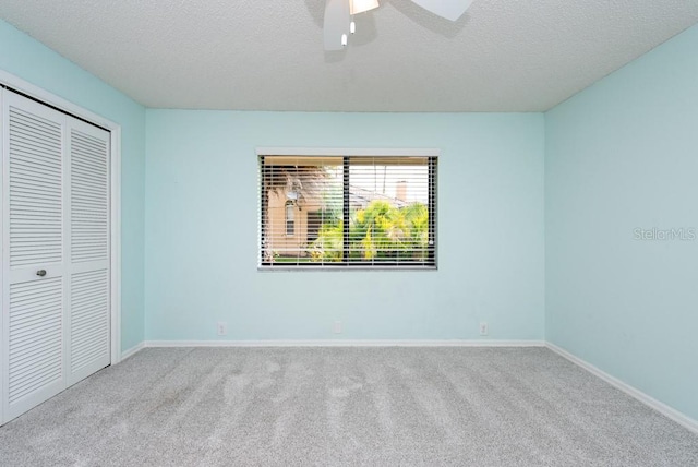 unfurnished bedroom with a closet, carpet, a textured ceiling, and ceiling fan