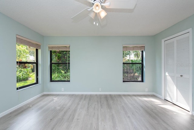 interior space with a textured ceiling, light wood-type flooring, and ceiling fan