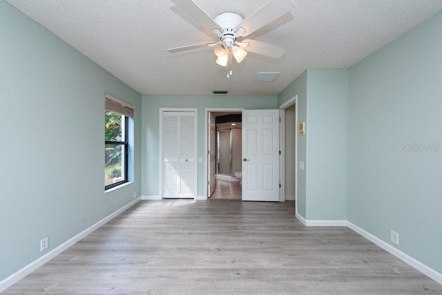 unfurnished bedroom with ceiling fan, light hardwood / wood-style floors, a closet, and a textured ceiling