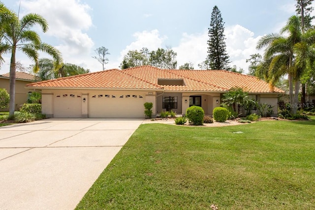 mediterranean / spanish home with a garage and a front lawn