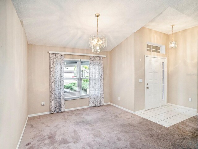 spare room featuring an inviting chandelier, tile patterned flooring, vaulted ceiling, and a textured ceiling