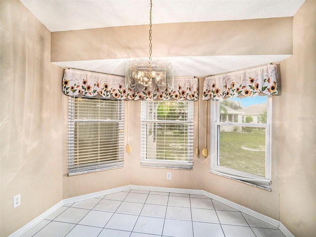 tiled empty room featuring a textured ceiling and a chandelier