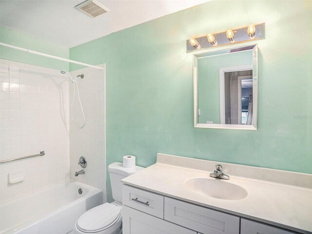 full bathroom featuring tiled shower / bath combo, toilet, and vanity