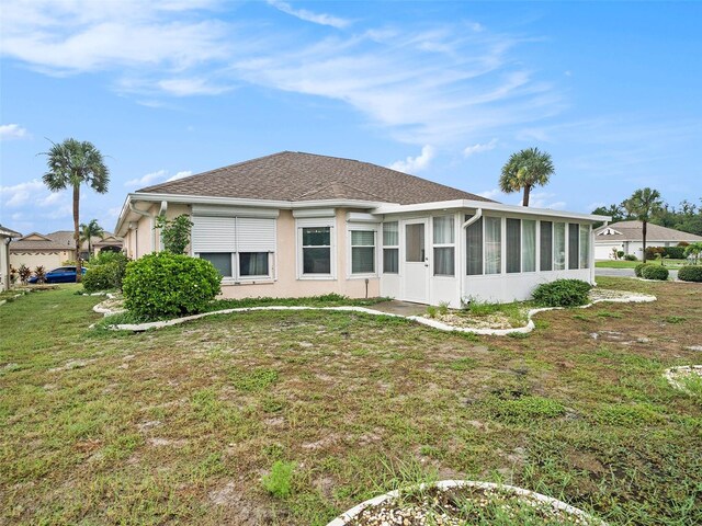 back of property with a yard and a sunroom