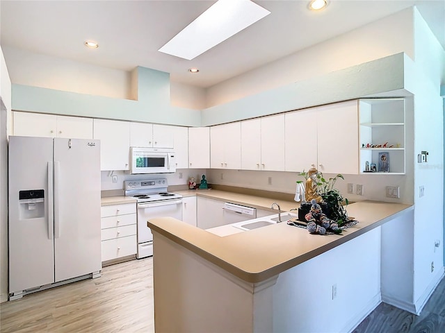 kitchen featuring light hardwood / wood-style flooring, white appliances, sink, a skylight, and white cabinetry