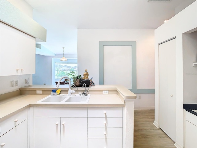 kitchen featuring light countertops, white cabinetry, a sink, and a peninsula