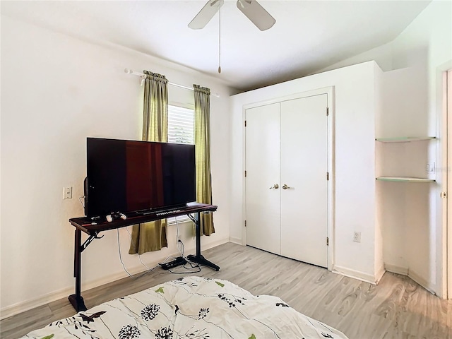 bedroom featuring light wood finished floors, a ceiling fan, baseboards, and a closet