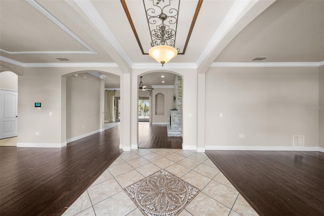 entrance foyer with crown molding, light hardwood / wood-style flooring, and a raised ceiling