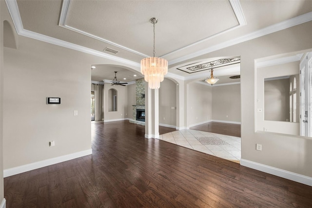 unfurnished room featuring hardwood / wood-style flooring, ornamental molding, a stone fireplace, and ceiling fan