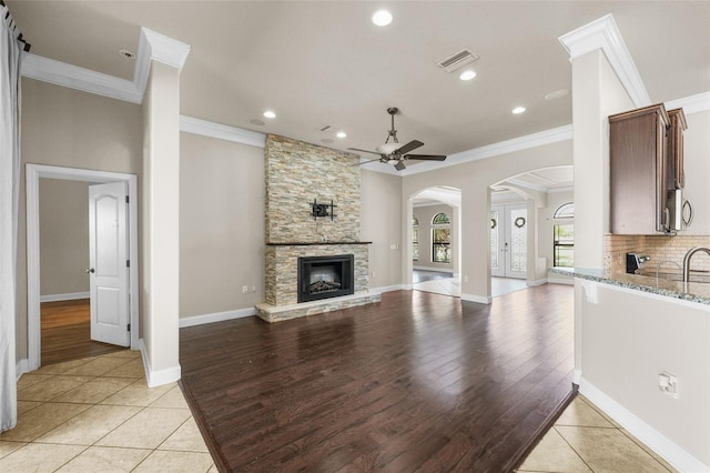 unfurnished living room featuring light tile patterned flooring, a fireplace, ceiling fan, and ornamental molding