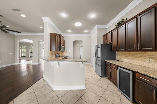 kitchen with ceiling fan, light wood-type flooring, wine cooler, kitchen peninsula, and backsplash