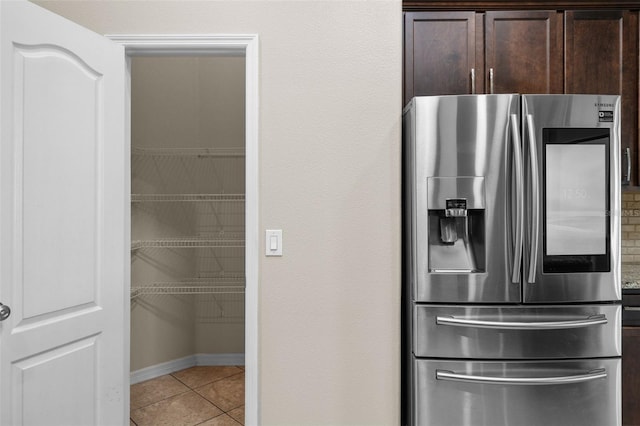 kitchen featuring dark brown cabinets, stainless steel refrigerator with ice dispenser, and light tile patterned floors