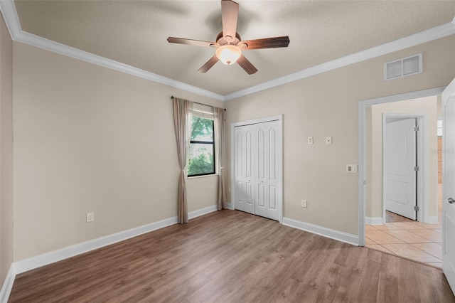 unfurnished bedroom featuring crown molding, a closet, light wood-type flooring, and ceiling fan