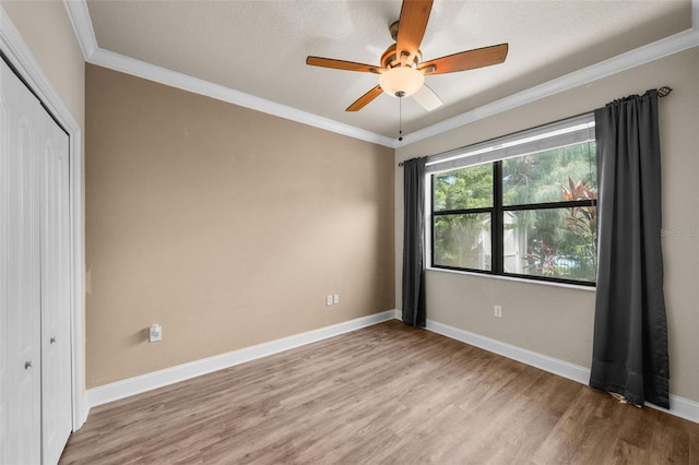 unfurnished bedroom with ceiling fan, hardwood / wood-style flooring, ornamental molding, and a closet