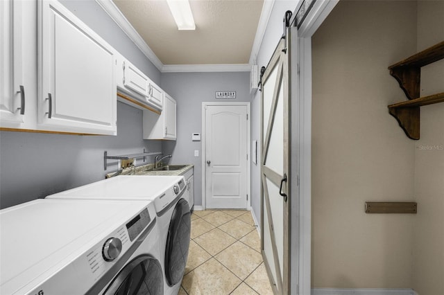 washroom with light tile patterned flooring, washing machine and dryer, ornamental molding, a barn door, and cabinets