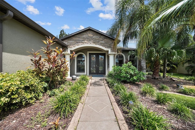 doorway to property with french doors, stucco siding, and stone siding