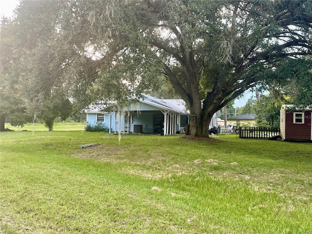 view of yard with a carport, a shed, an outdoor structure, and fence