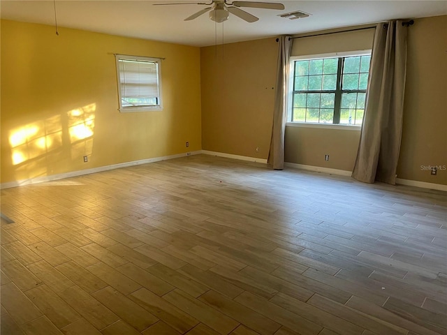 empty room featuring light wood-type flooring, ceiling fan, visible vents, and baseboards