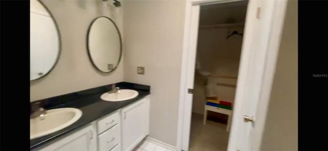 bathroom with double vanity, a sink, and a walk in closet