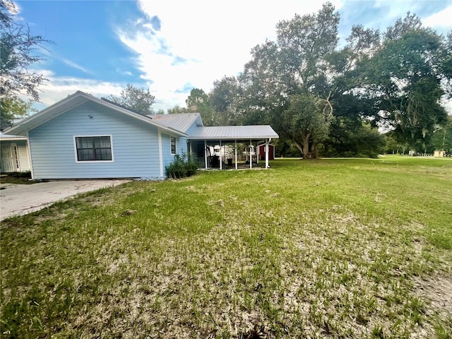 rear view of house with metal roof and a lawn