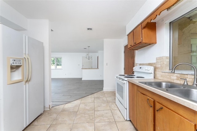 kitchen with white appliances, light wood-type flooring, backsplash, hanging light fixtures, and sink