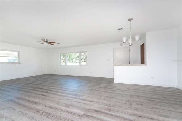 interior space with light wood-type flooring and ceiling fan with notable chandelier