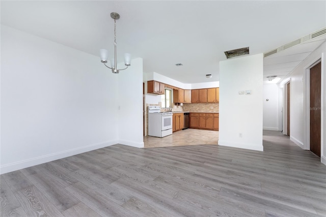 unfurnished living room featuring a chandelier and light wood-type flooring