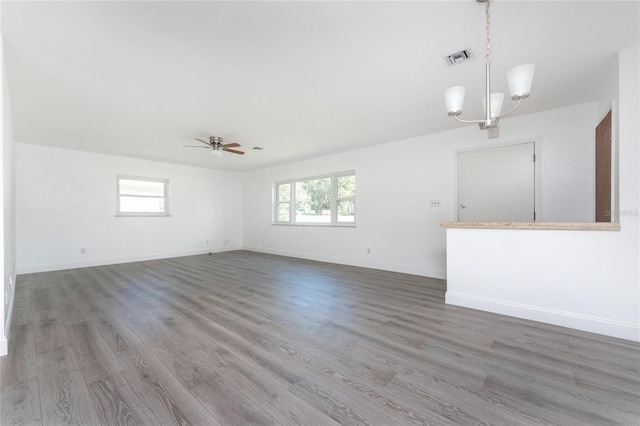 unfurnished living room with ceiling fan with notable chandelier and hardwood / wood-style flooring