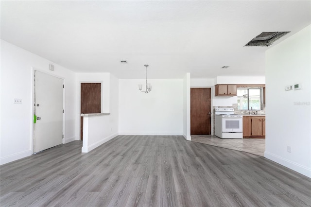 unfurnished living room featuring sink, light hardwood / wood-style floors, and a notable chandelier