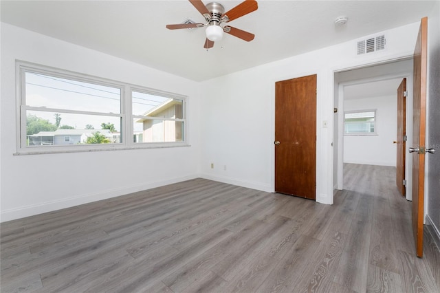 unfurnished bedroom featuring multiple windows, ceiling fan, and light wood-type flooring