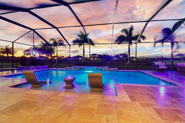 pool at dusk featuring pool water feature, a patio area, and a lanai