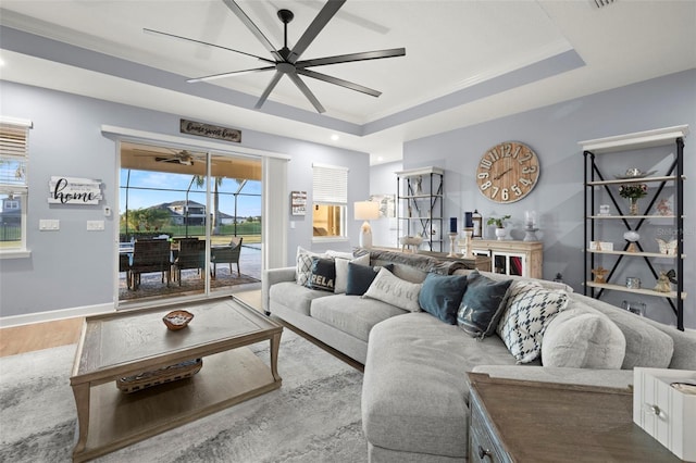 living room with a tray ceiling, wood-type flooring, and ceiling fan