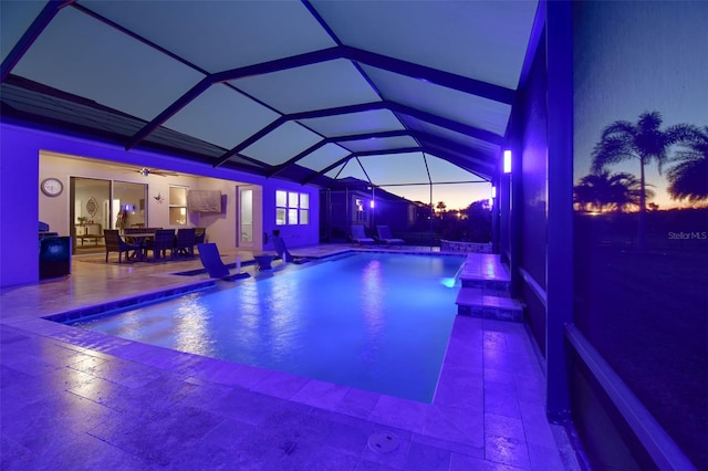 view of swimming pool featuring ceiling fan, a lanai, and a patio