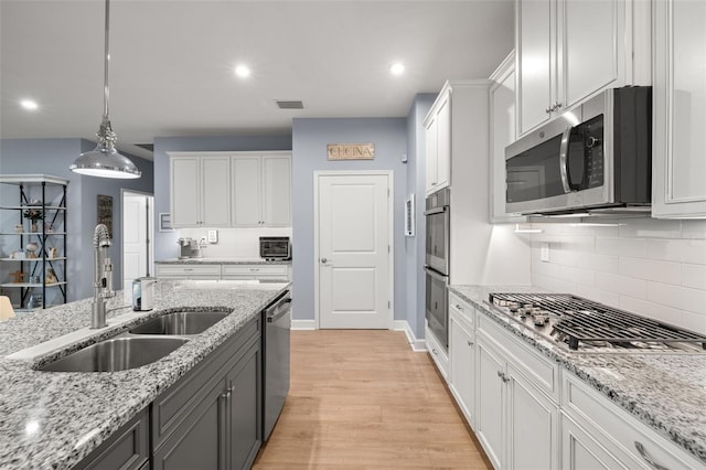 kitchen featuring hanging light fixtures, white cabinetry, appliances with stainless steel finishes, and sink