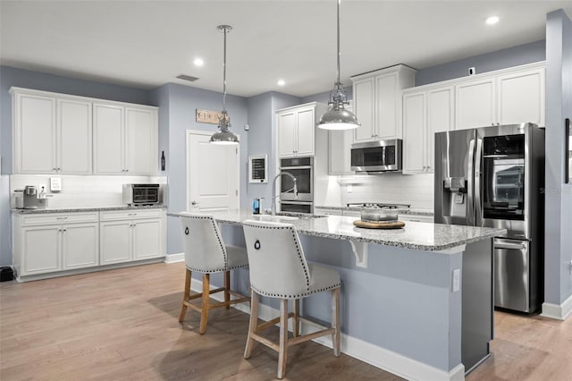 kitchen featuring white cabinetry, an island with sink, appliances with stainless steel finishes, and sink