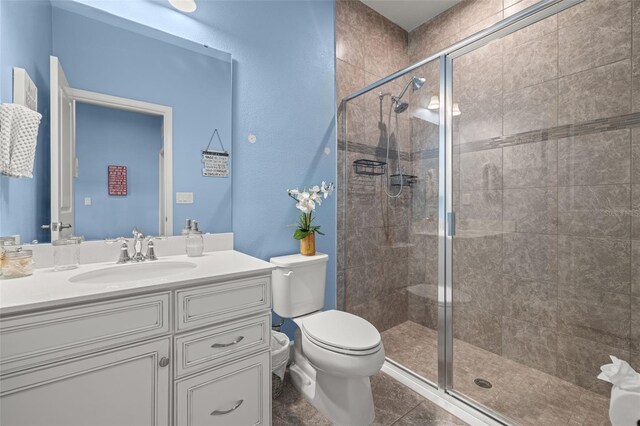 bathroom with vanity, tile patterned flooring, toilet, and walk in shower