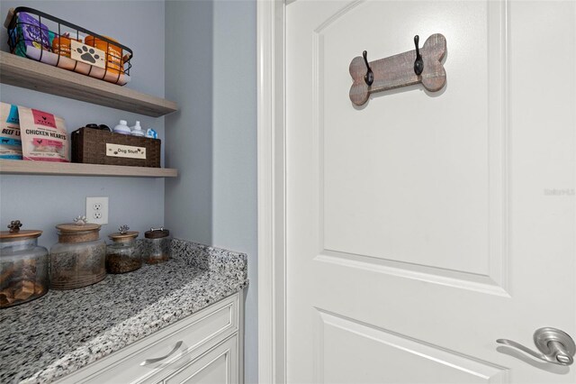 bar featuring white cabinetry and light stone countertops