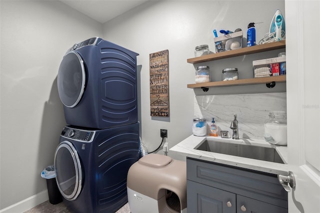 laundry area featuring cabinets, stacked washer / drying machine, and sink