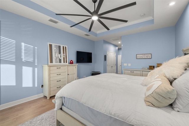 bedroom featuring crown molding, a closet, light wood-type flooring, and a tray ceiling